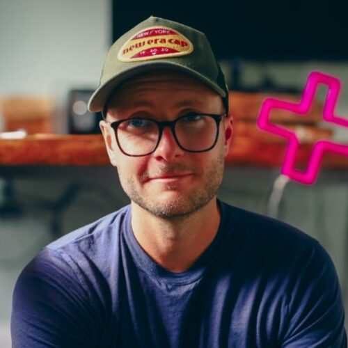 headshot of joe glover, a man with a hat on